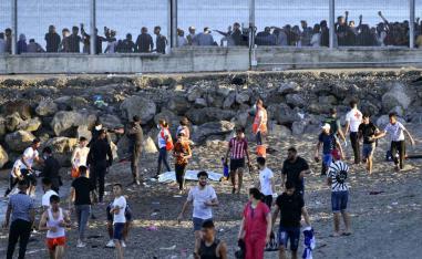 Spanish Guardia Civil officers try to stop people from Morocco entering into Ceuta