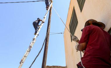عمال ليبيون يصلحون خط كهرباء في طرابلس