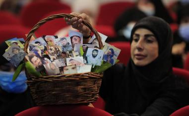 ناشطة في حزب الله تحمل سلة بصور لمقاتلين لبنانيين وايرانيين قتلى