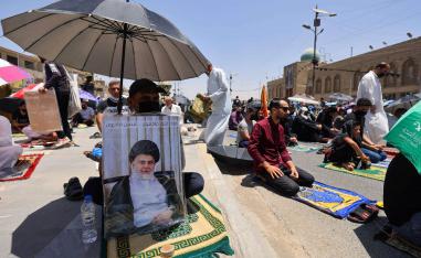 عراقيون يرفعون صورا للصدر أثناء صلاة الجمعة في مدينة الصدر في بغداد