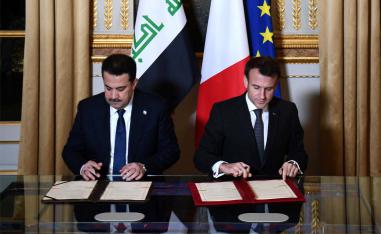 French President Emmanuel Macron and Iraq's Prime Minister Mohammed al-Sudani sign documents at the Elysee Presidential Palace