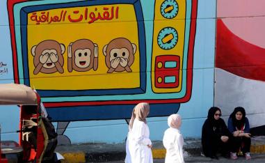 عراقيات بجانب جدارية تنتقد القنوات العراقية