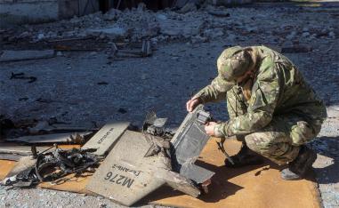 A Ukrainian police officer inspects parts of a drone, what Ukrainian authorities consider to be an Iranian made suicide drone Shahed-136