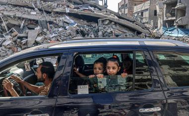 أطفال فلسطينيون في سيارة يغادرون مدينة غزة على خلفية دمار القصف الاسرائيلي