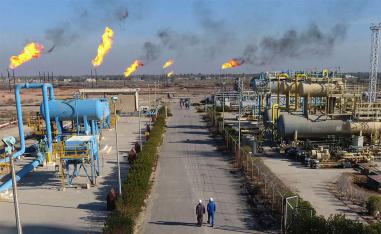 Labourers walk down a path in the Nihran Bin Omar field north of Basra