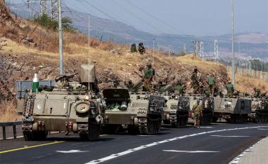 A convoy of Israeli Armoured Personnel Carriers drives on a road near Israel's border with Lebanon
