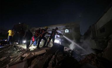 Firefighters spray water on the rubble of a building following Israeli bombardment in Rafah