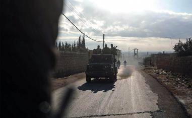 Fighters from Hayat Tahrir al-Sham (HTS) ride in military vehicles in the eastern outskirts of the town of Atarib,