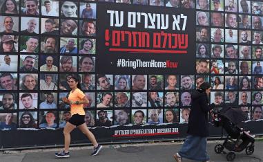 People walk past a billboard bearing the portraits of Israeli hostages, held in the Gaza Strip since the October 7, 2023 attacks by Hamas, in Jerusalem