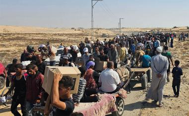 Displaced Palestinians walk along a road to receive humanitarian aid packages from a US-backed foundation in Rafah in the southern Gaza Strip on June 