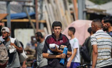  Displaced Palestinians at the Nuseirat refugee camp haul food parcels and other items they managed to get from a GHF aid distribution point at the so-called Netzarim corridor 