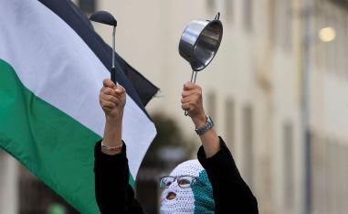 A pro-Palestinian activist makes noise with a pot in a protest over the hunger crisis in Gaza, outside the parliament in Cape Town