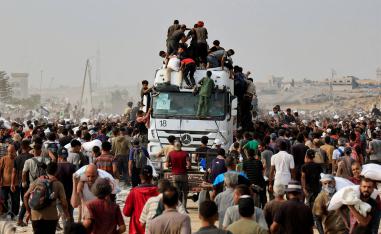 Palestinians scramble to collect aid supplies from trucks that entered through Israel, in Khan Younis