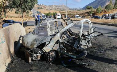 Lebanese emergency and security service members deploy around the wreckage of a car hit by an Israeli drone attack in the southern area of Al-Jarmak 