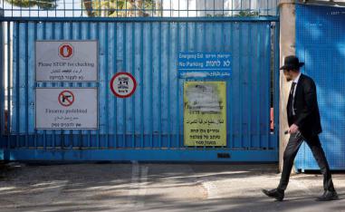 Signs are displayed at the gate of the UNRWA headquarters as a Jewish man walks outside, in Jerusalem December 8, 2025. 
