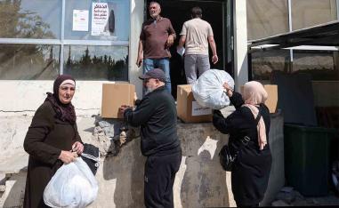 People receive food packages and other aid at the municipality center in Tyre