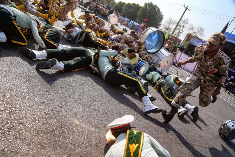 A soldier running past injured comrades lying on the ground at the scene of an attack in Ahvaz