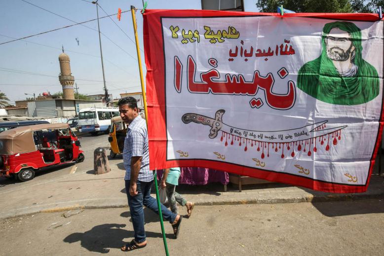 عراقي يمر بالقرب من لافتة طائفية في مدينة الصدر ببغداد