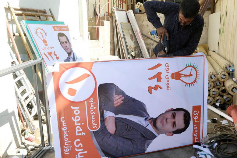 كردي عراقي يثبت ملصقا في السليمانية للانتخابات الكردية المقبلة