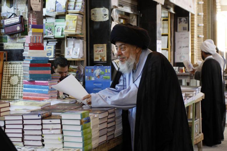رجل دين يقف عند مكتبة تبيع كتبا دينية في النجف