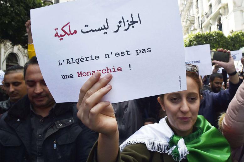 An Algerian protester holds a sign which reads in Arabic and French: "Algeria is not a monarchy" 