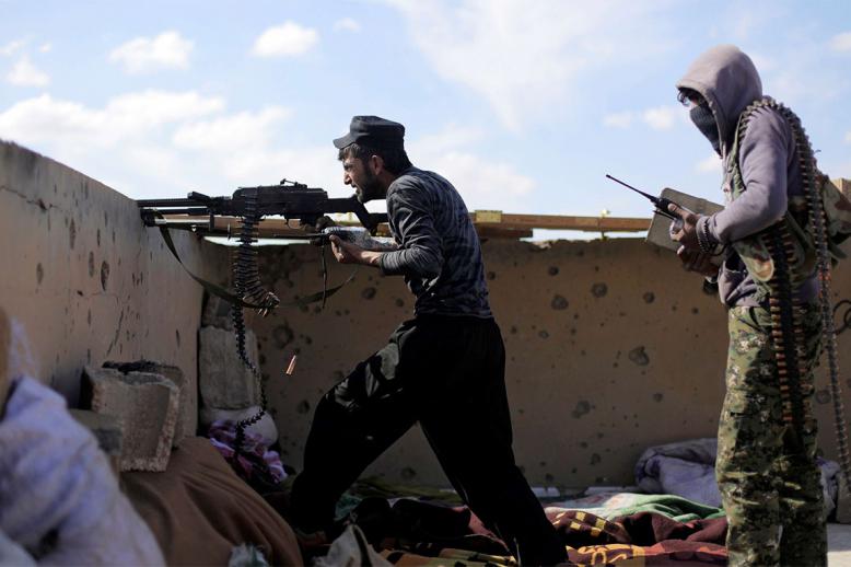 A fighter of Syrian Democratic Forces (SDF) fires a weapon in Baghouz