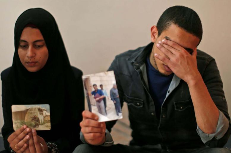 The daughter (L) and son of Zaki Mubarak hold his picture