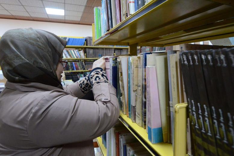 امرأة عراقية تفرز الكتب في المكتبة الجديدة لجامعة الموصل