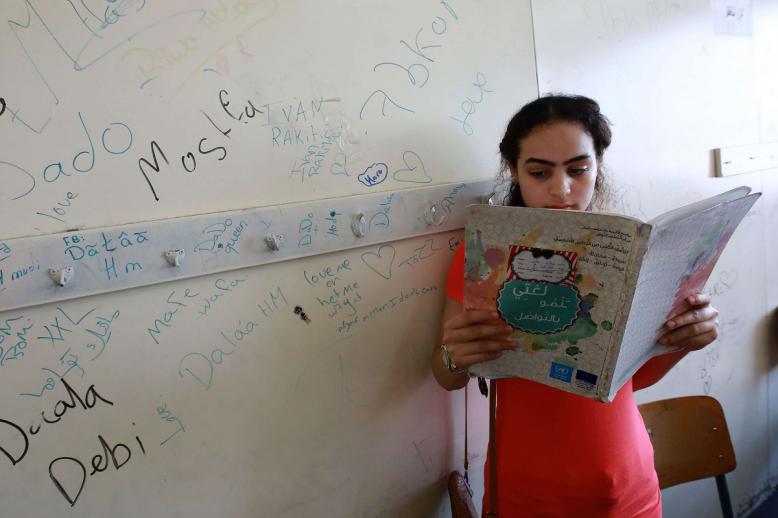طفلة فلسطينية تقرأ قصة في مخيم بلبنان