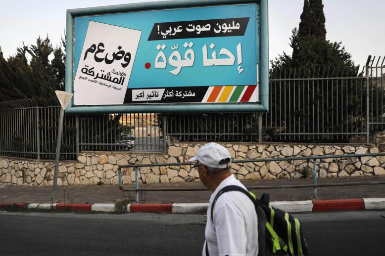 فلسطيني يمر بجانب اعلان للتصويت في الانتخابات الاسرائيلية