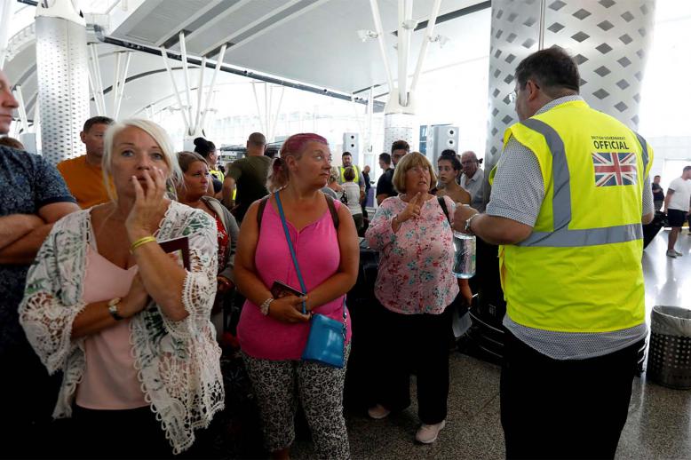 A British government official speaks to tourists, flying with Thomas Cook at Enfidha-Hammamet International Airport