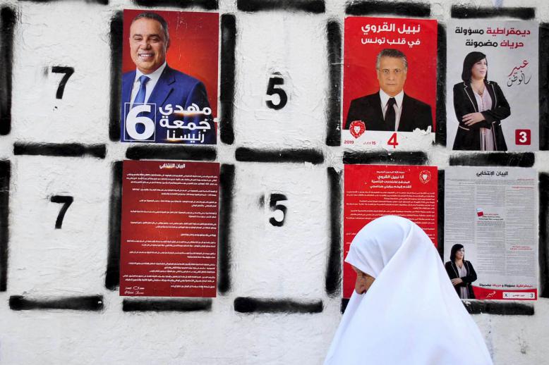 تونسية تمر من مجموعة صور وملصقات لمرشحي الرئاسة