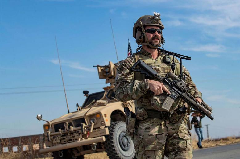 A US soldier stands by an armoured vehicle during a patrol of the northern countryside of the northeastern Syrian town of al-Malikiyah 