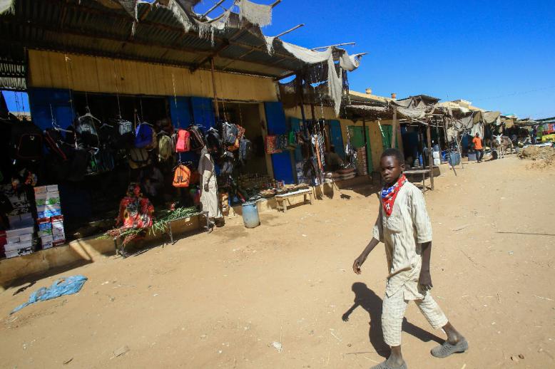 A diplaced Sudanese boy walks through the market of the Abu Shouk camp for internally displaced persons