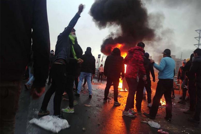 Iranian protesters gather around a fire during a demonstration against an increase in gasoline prices in the capital Tehran