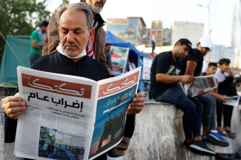 An Iraqi demonstrator reads Tuktuk newspaper during the ongoing anti-government protests in Baghdad