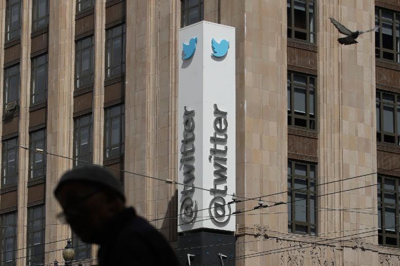 A pedestrian walks across the street from the Twitter office building in San Francisco