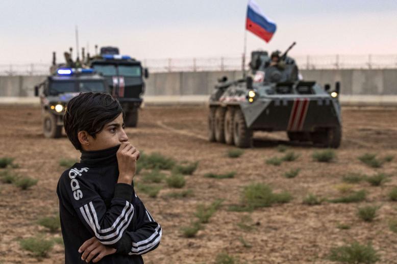 A young boy stands in front of Russian military vehicles in Syria's northeastern Hasakeh province