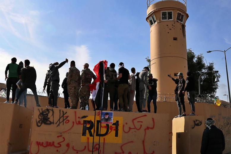 Pro-Iranian militiamen and their supporters look into the US embassy compound in Baghdad