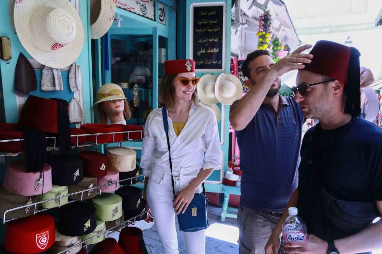 A tourist tries on a Tunisian “chechia” (traditional fez) in a shop at a bazaar in the Medina (old town) of Tunis