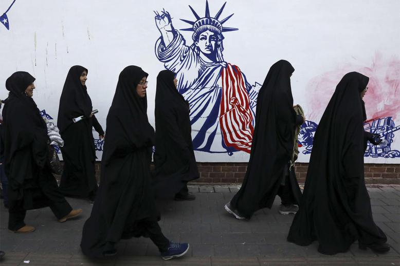 Iranian women passing a satirical drawing of the Statue of Liberty painted on the wall of the former US Embassy in Tehran