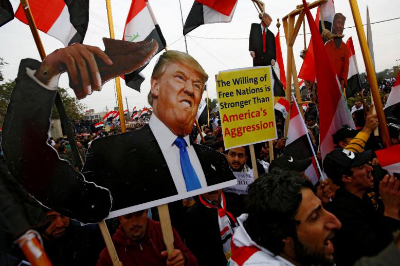 Supporters of Iraqi Shi'ite cleric Moqtada al-Sadr carry placards depicting US President Donald Trump