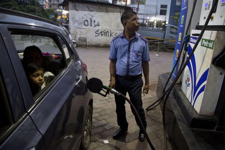 Indians get fuel filled in their car at a petrol pump in Gauhati, India