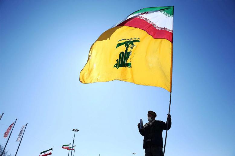 An Iranian carries the Iranian and Hezbollah flags during the commemoration of the 41st anniversary of the Islamic revolution in Tehran
