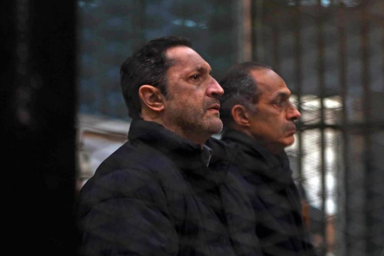 Alaa and Gamal Mubarak, sons of former Egyptian president Hosni Mubarak, sit inside the defendants' cage at the Police Academy courthouse in Cairo