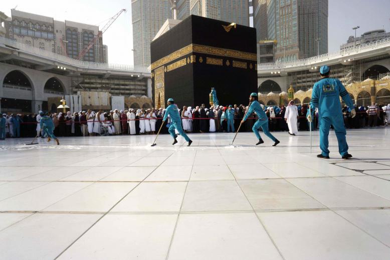 Workers sterilize the ground in front of the Kaaba