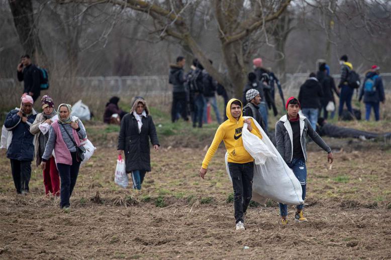 Migrants walk on the field near the Turkey's Pazarkule border crossing with Greece's Kastanies