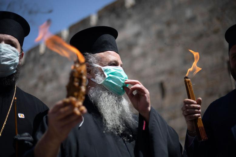 Orthodox clergymen hold candles lit from fire of the Church of the Holy Sepulchre