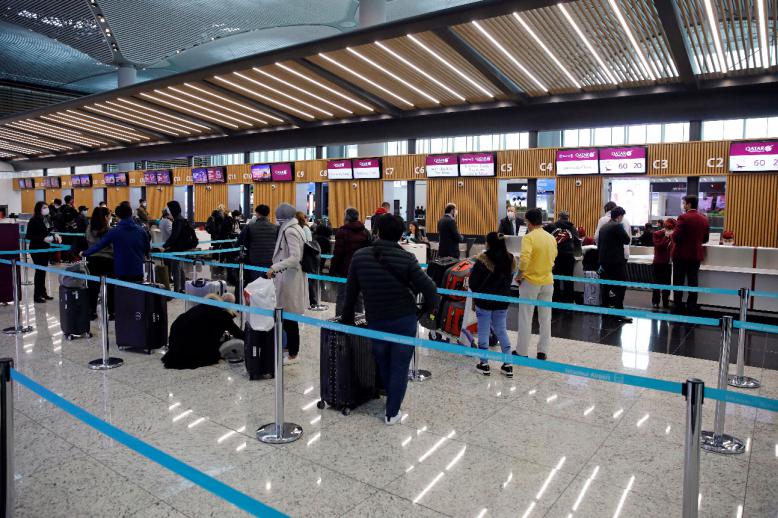 Passengers wearing protective face masks queue for a check-in, during the outbreak of the coronavirus disease (COVID-19), at Istanbul Airport