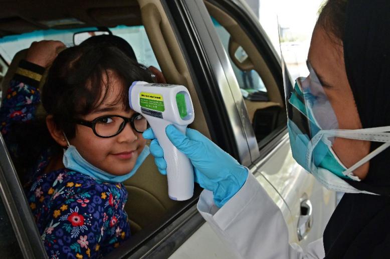 A nurse measures the body temperature of a young girl at a drive thru testing centre for COVID-19 in Abu Dhabi